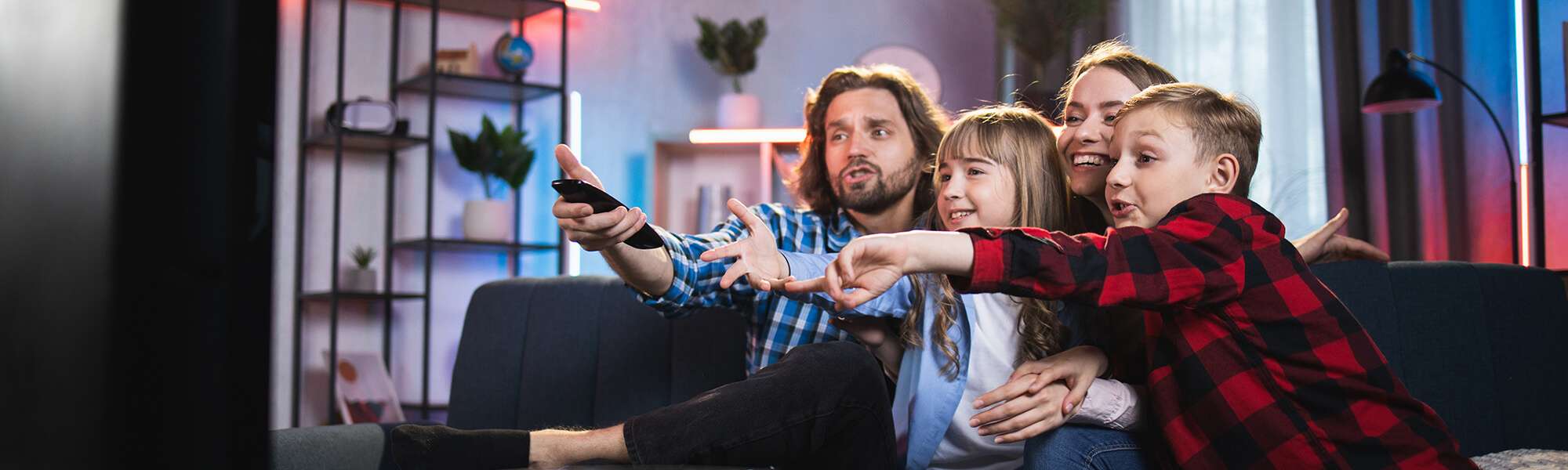 family pointing at television in house