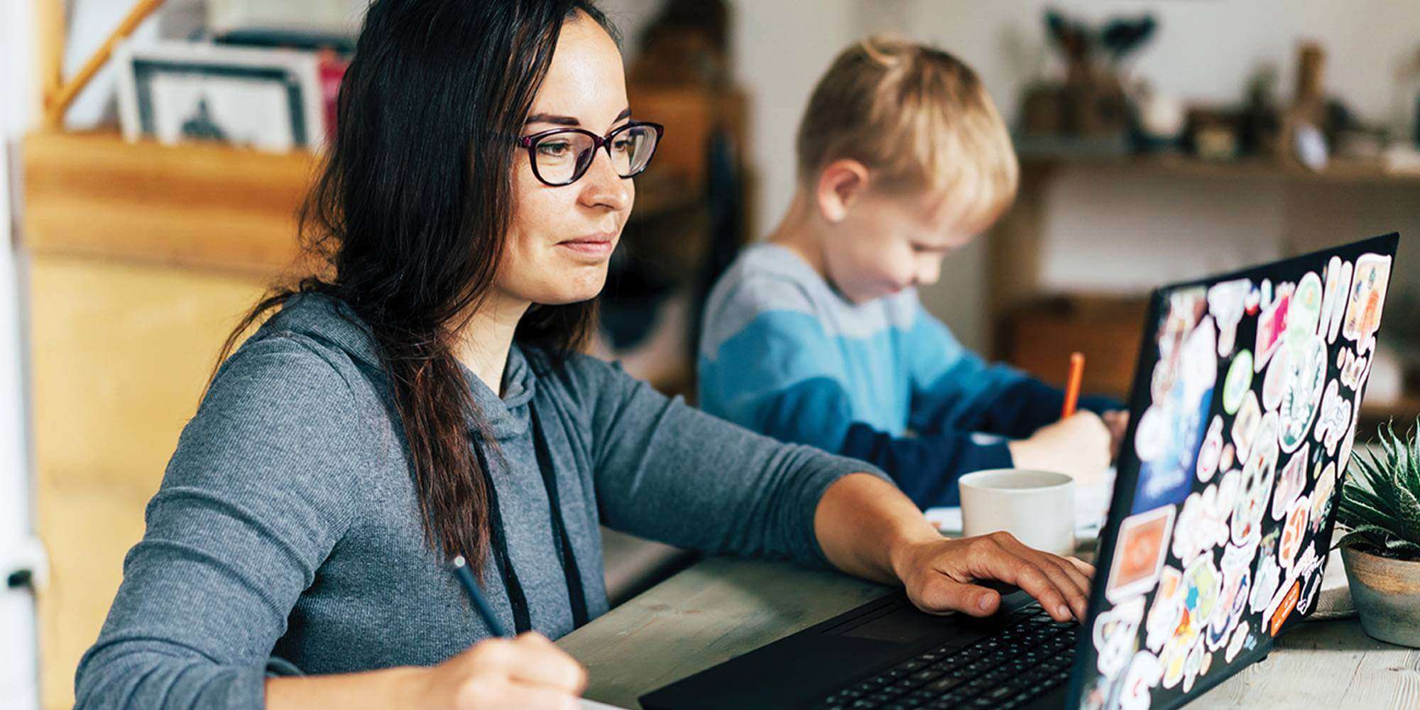 Mom works on bills while young son does his homework.